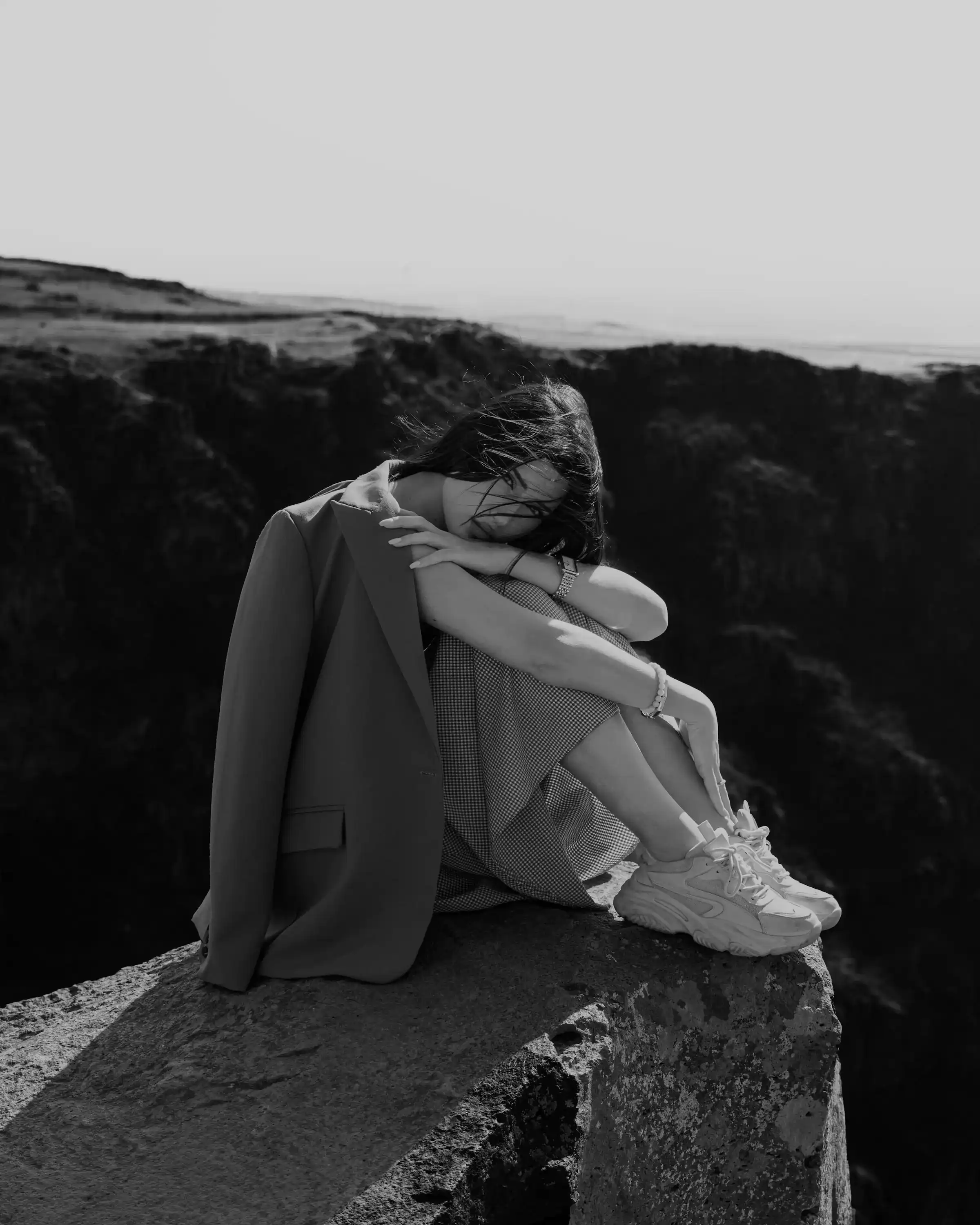 Contemplative individual sitting on a cliff, reflecting Colectivo Orgánico's ethos of mindfulness and connection with nature.